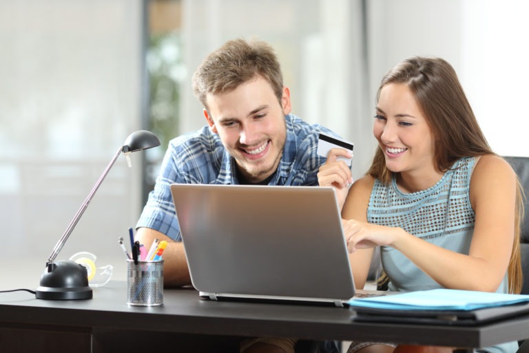 man and woman in front of lap top computer with credit card